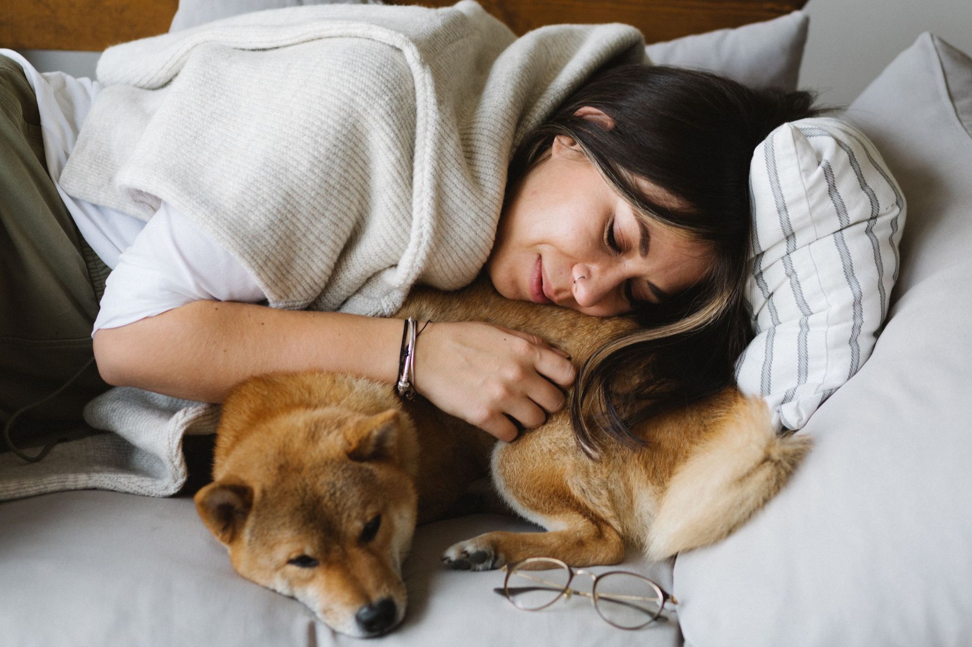 A woman resting on the couch with her Shiba Inu